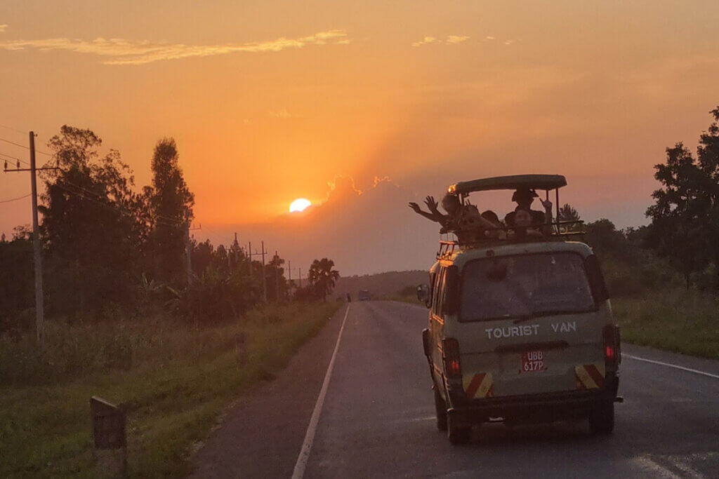 Why Travel East Africa with Ebonjalo Tours Tourists of Ebonjalo in an open top safari van driving towards the sunset in Uganda