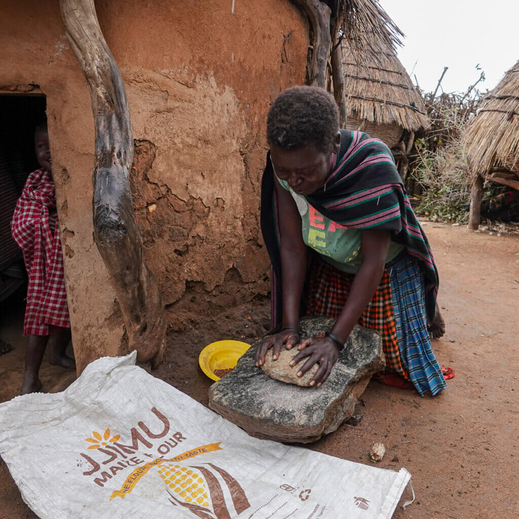 12 Day Kenya and Uganda Safari: Masai Mara & Karamoja A woman in nakapelemoru is grinding mais to make posho